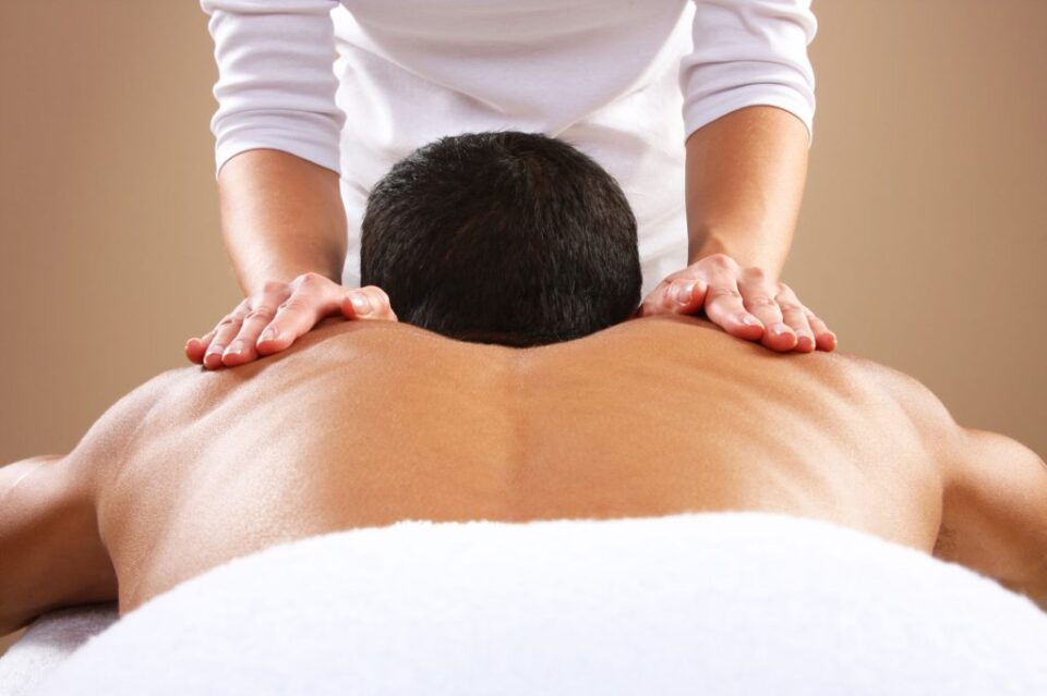 person with bareback covered with towel receiving massage